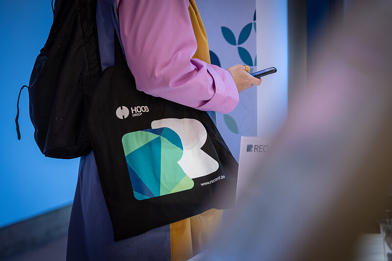 A person is holding a bag with a logo in their hand.