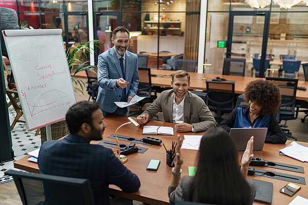 A group of people are sitting at a table in an office and discussing something.