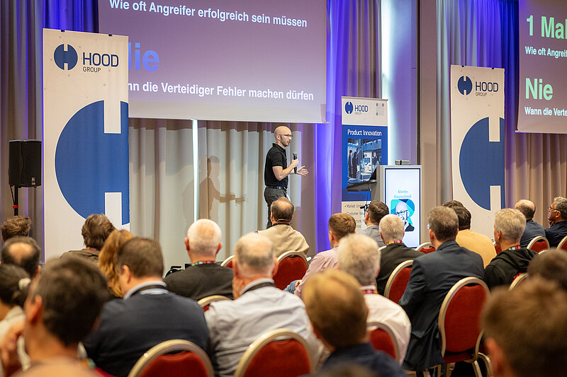 A man gives a presentation at a conference in front of an audience.