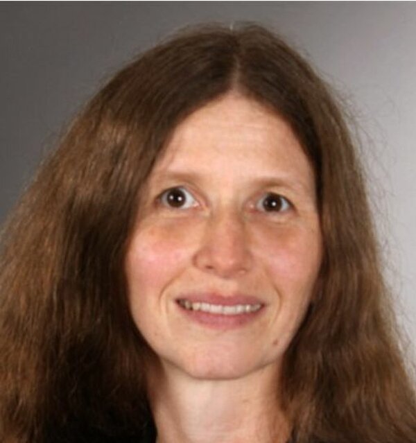 Eine Frau mit langen Haaren trägt ein schwarzes Shirt.