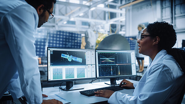 Two colleagues are consulting satellite design on the computer