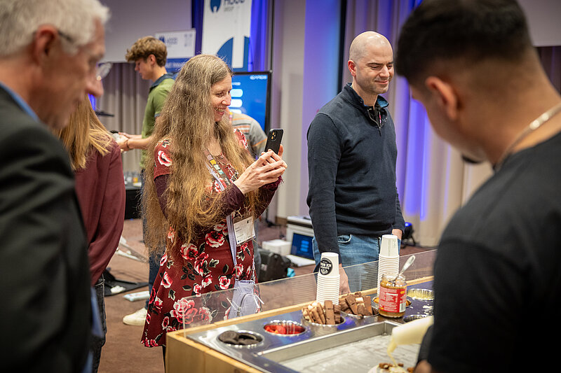 People are standing around a table with various foods and drinks.