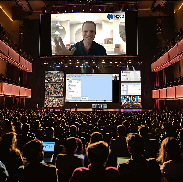 A man stands on stage in front of a large screen.