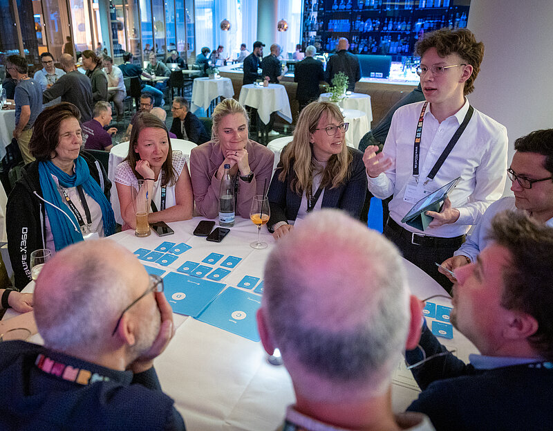 A group of people are sitting around a table at a conference and having a lively discussion.